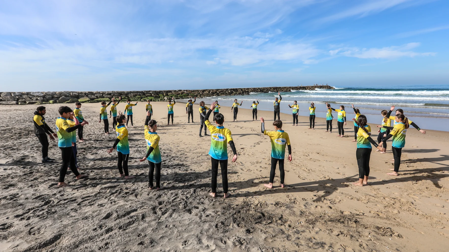 Grupo na praia com lycras personalizadas para escola de surf